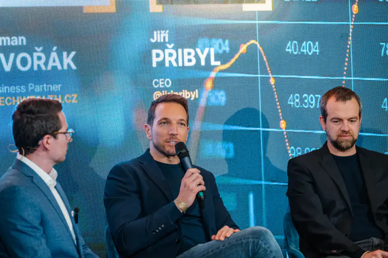 Two speakers presenting against a data-led stage screen