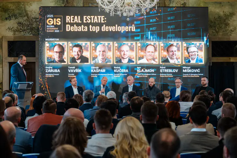 Conference stage and audience beneath a wide presentation screen