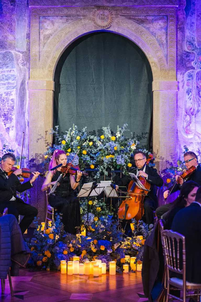 Live string performance beside floral arrangements at an evening reception