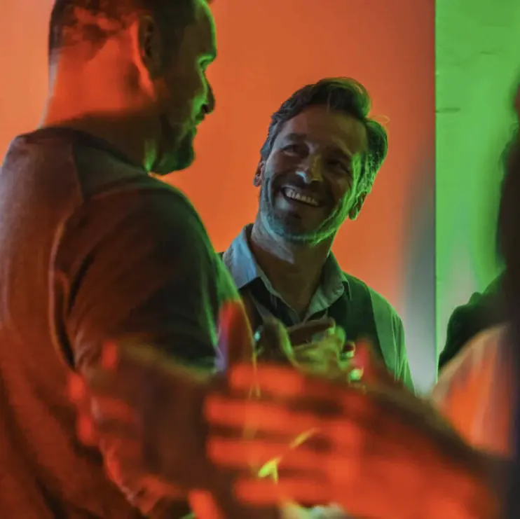 Guests enjoying a lively conversation under colourful event lighting