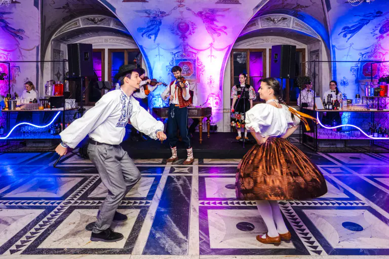 Live dancers performing for guests in a dramatically lit historic Prague hall