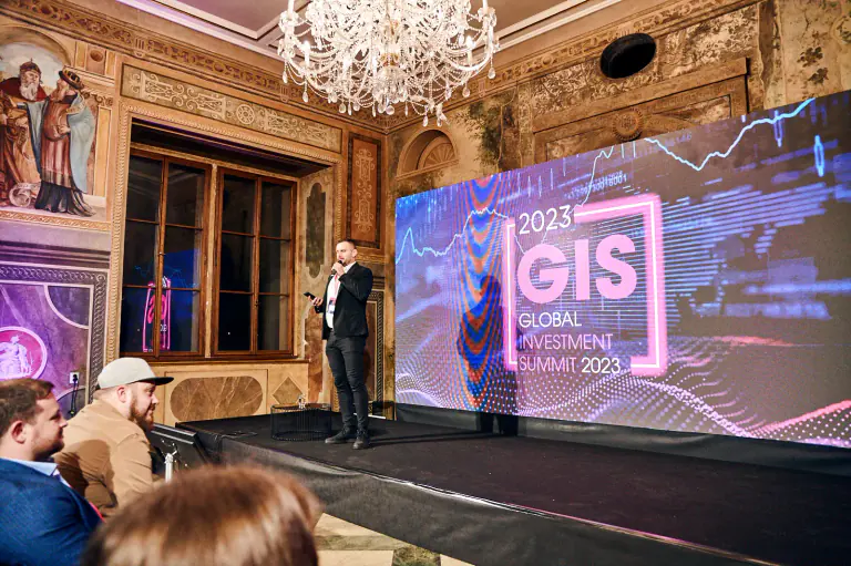 Global Investment Summit 2023 speaker beside a large stage screen at Martinic Palace