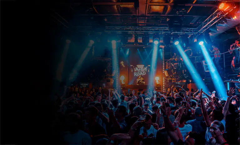 Crowd dancing beneath blue stage lights inside Duplex Prague