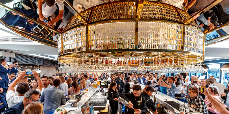Crowded bar beneath a mirrored drinks display at Fly Vista / LEVELS