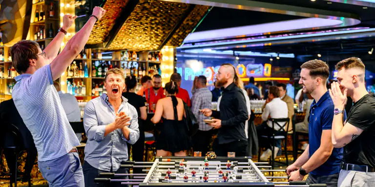 Guests celebrating around a foosball table at Fly Vista / LEVELS