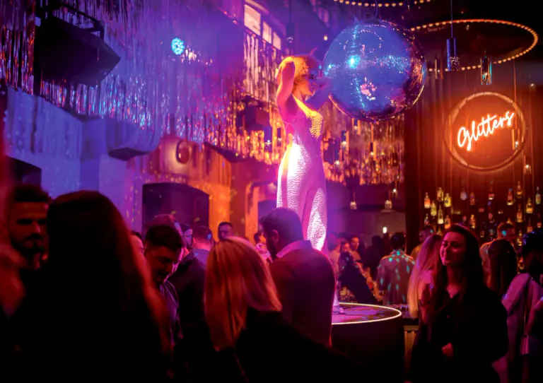 Performer and guests beneath colourful lights inside Moon Club Prague