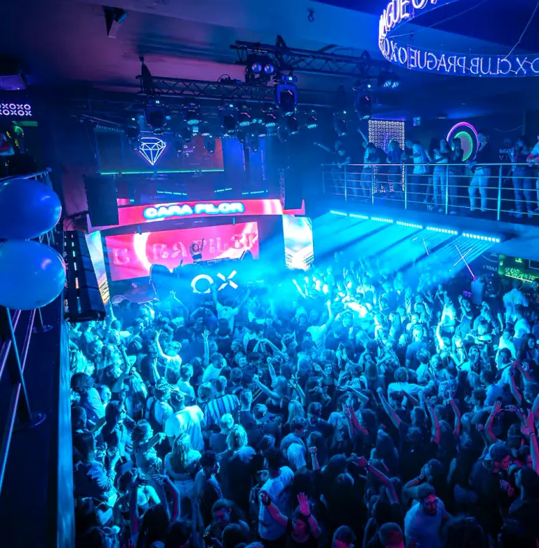 Crowd dancing beneath blue lighting at OX Club Prague
