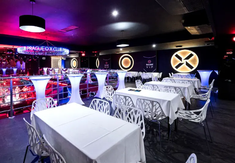 OX Club Prague lounge with white dining tables and illuminated logos