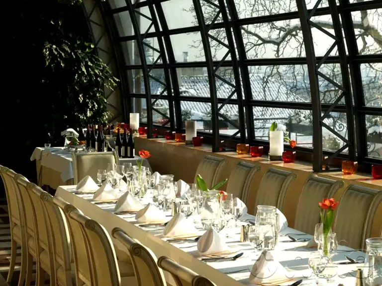 Long dinner table set inside Villa Richter’s glass-walled pavilion